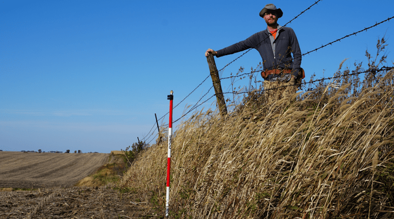 Isaac Larsen standing on the erosional escarpment at Stinton Prairie, Iowa. CREDIT: UMass Amherst