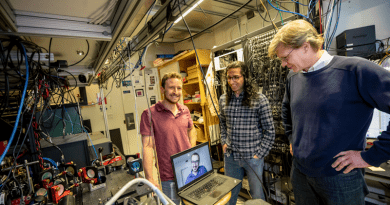 Dolev Bluvstein, Harry Levine (on the laptop), Sepehr Ebadi and Mikhail Lukin, on right, standing next to their neutral atom quantum computer, on left. Their new quantum processor can move atoms while preserving their quantum entanglement, enabling new types of computations where any two qubits can be entangled, even if they are far apart. Credit: Rose Lincoln/Harvard Staff Photographer
