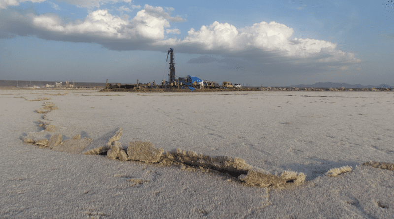 During the dry season, evaporating water leaves behind trona crystals, which grow on the lakebed of Lake Magadi, the southernmost lake in the Kenyan Rift Valley. A drilling rig used in the study is seen towering above the dry lakebed. CREDIT: Andrew Cohen/University of Arizona
