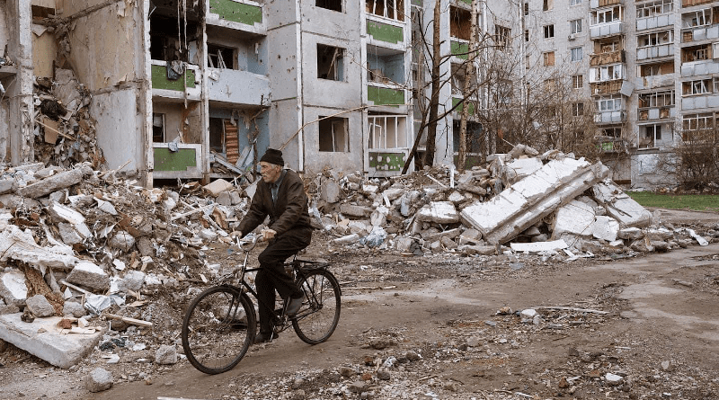 A man rides a bicycle through the rubble after Russian attack. Photo Credit: Ukraine Defense Ministry