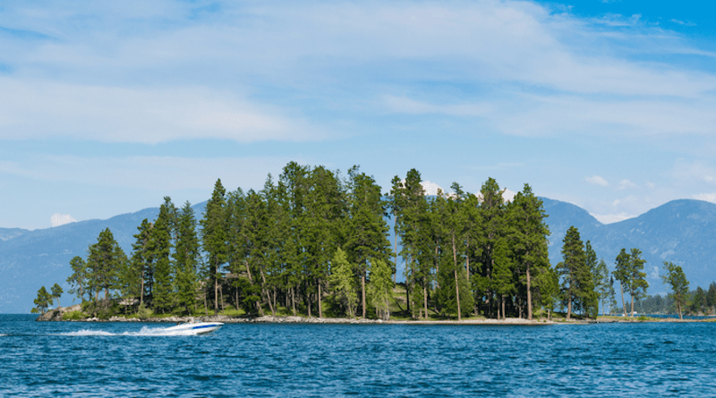 A boater cruises by an island at Montana's Flathead Lake. CREDIT: University of Montana photo