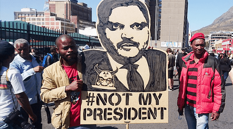 A protest placard depicting Atul Gupta at a Zuma Must Fall protest in Cape Town. The slogan "#Not My President" on the placard explicitly links Atul Gupta with President Zuma. Photo Credit: Discott, Wikipedia Commons