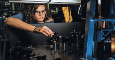 National Institute of Standards and Technology physicist Katie McCormick adjusts mirror to steer laser beam used to cool trapped beryllium ion, as part of efforts to improve quantum measurements and quantum computing. Photo Credit: NDU