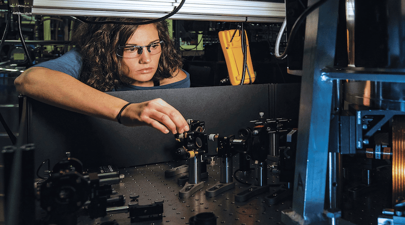 National Institute of Standards and Technology physicist Katie McCormick adjusts mirror to steer laser beam used to cool trapped beryllium ion, as part of efforts to improve quantum measurements and quantum computing. Photo Credit: NDU