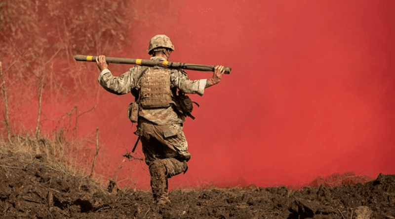 A soldier runs through red smoke with a Bangalore torpedo during Exercise Garuda Shield at the Baturaja Training Area, Indonesia, Aug. 12, 2021. U.S. Army/U.S. Department of Defense