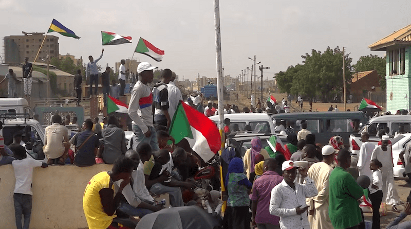 Sudanese protestors gather in front of government buildings in Khartoum to celebrate the final signing of the Draft Constitutional Declaration between military and civil representatives. Photo Credit: VOA, Wikipedia Commons