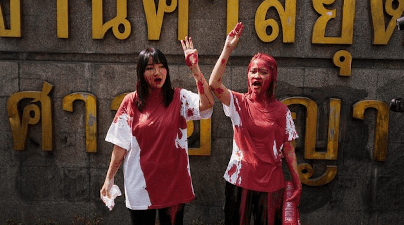 Orawan Phuphong (left) and Tantawan “Tawan” Tuatulanon stain their clothes with red paint and give the three-fingered salute, a protest sign inspired by the “Hunger Games” movies, as they call for authorities to grant bail to other political activists, Jan. 16, 2023. Photo Credit: Sunthorn Chongcharoen/BenarNews