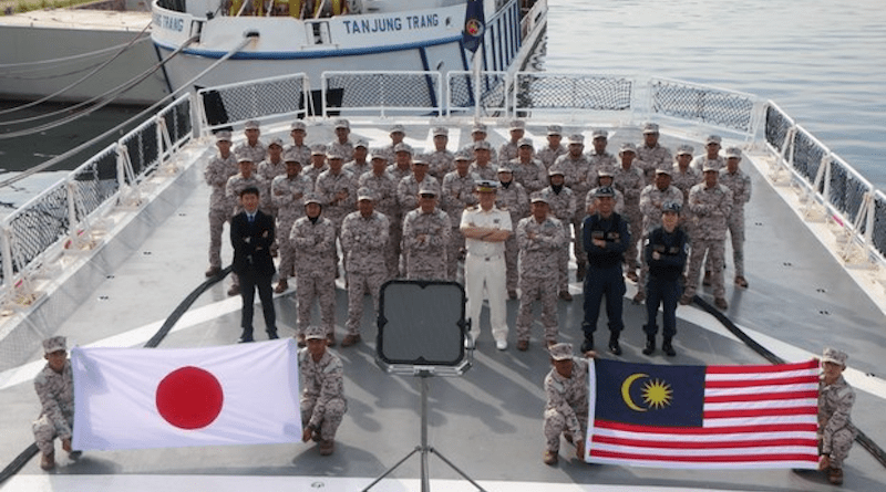 Officers and members of the Malaysian Maritime Enforcement Agency (right) and their counterparts from Japan Coast Guard display their countries’ flags at the end of a drill in Kota Kinabalu, Sabah, Malaysia, Jan.13, 2022. [Photo courtesy Malaysian Maritime Enforcement Agency]