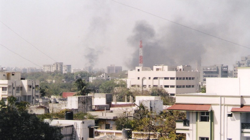 The skyline of Ahmedabad, Gujarat, India filled with smoke as buildings and shops are set on fire by rioting mobs. Photo Credit: Aksi great, Wikipedia Commons