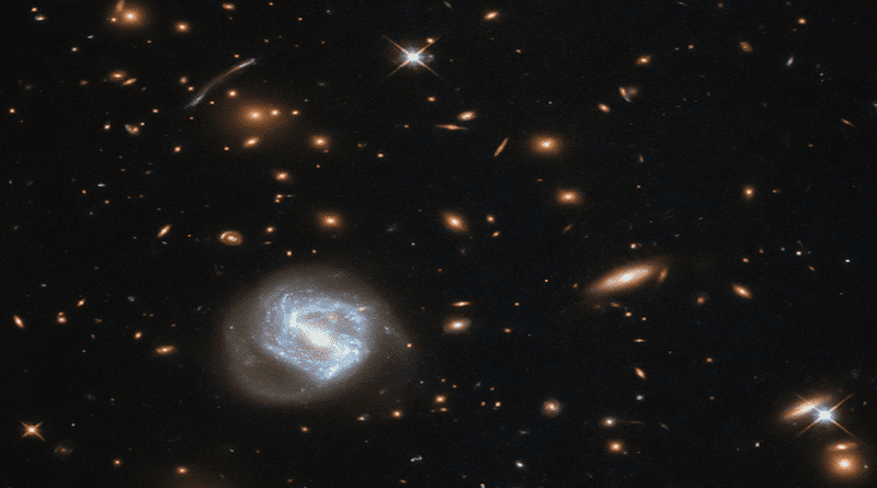 This image taken by NASA's Hubble Space Telescope shows a spiral galaxy (bottom left) in front of a large galaxy cluster. New research leveraged an artificial tool to estimate the masses of galaxy clusters more accurately. CREDIT: ESA/Hubble & NASA
