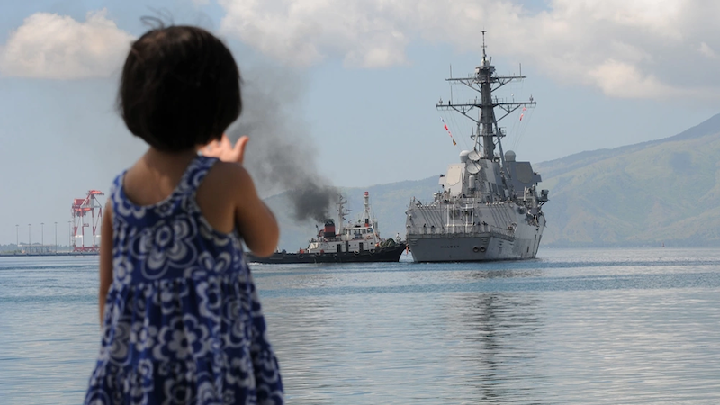 A Filipino child waves as the guided-missile destroyer USS Halsey gets underway after participating in Cooperation Afloat Readiness and Training Philippines. Photo Credit: Petty Officer 1st Class Thomas Brennan, US Navy