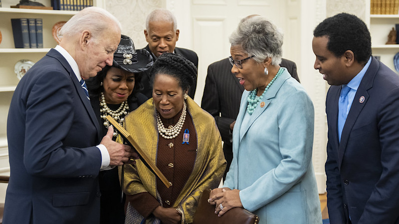 President Joe Biden shares a framed photo with members of the Congressional Black Caucus, Monday, March 7, 2022, in the Oval Office. (Official White House Photo by Adam Schultz)