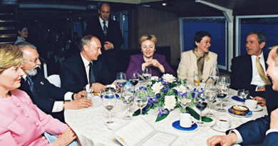 Yevgeny Prigozhin (standing in background) hosting Russian President Putin and US President George W. Bush on his floating restaurant New Island in St. Petersburg on 25 May 2002. Photo Credit: Kremlin.ru, Wikipedia Commons