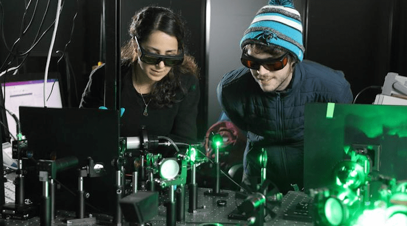 Doctoral candidates Sara Makarem Hoseini and Daniel Hirt observe the plasma ray setup. Though Hirt wears a knit cap and puffy jacket for effect, the cooling is localized and doesn’t have much influence on the surrounding room temperature. CREDIT: Tom Cogill