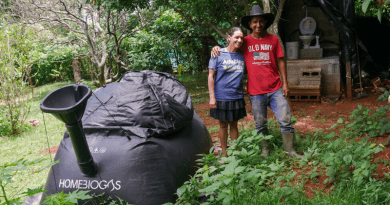 Marisol and Misael Menjívar pose next to the biodigester installed in March in the backyard of their home in El Corozal, a rural settlement located near Suchitoto in central El Salvador. With a biotoilet and stove, the couple produces biogas for cooking from feces, which saves them money. The biotoilet can be seen in the background. CREDIT: Edgardo Ayala / IPS