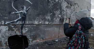 A teenager takes a photograph of a work by British street artist Banksy in the spring of 2023 in Irpin, Ukraine. Photo Credit: © UNICEF/Filippov
