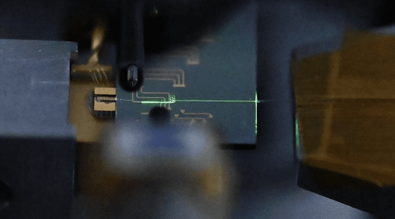 A nanophotonic mode-locked laser built on lithium niobate emits a beam of green laser light. CREDIT: Caltech