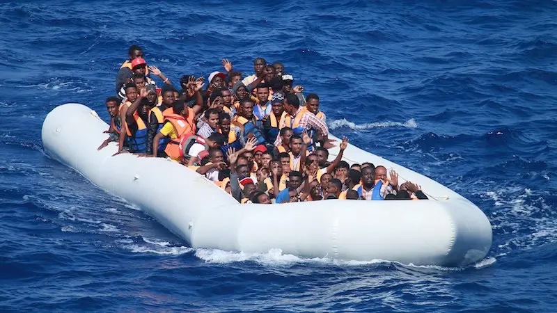 File photo of migrants aboard an inflatable vessel before their rescue near Spain. Photo Credit: U.S. navy photo by Chief Information Systems Technician Wesley R. Dickey, Wikipedia Commons