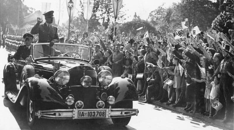 Adolf Hitler waving to people from his car. Photo Credit: Bundesarchiv, Wikipedia Commons