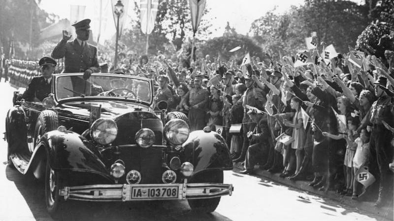 Adolf Hitler waving to people from his car. Photo Credit: Bundesarchiv, Wikipedia Commons
