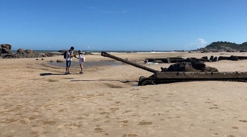 Tourists taking pictures in front of a military tank, half buried in the sand on a beach in Kinmen, Aug. 20, 2022. (RFA)