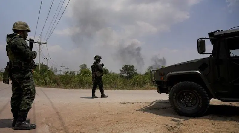 Smoke billows across the border in Kayin, Myanmar, as Thai soldiers stand watch in Mae Sot, Thailand, April 20, 2024. Photo Credit: Pimuk Rakkanam/RFA