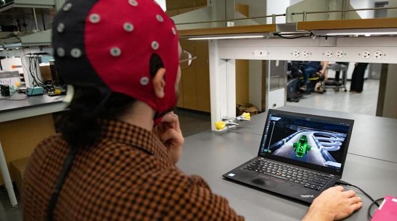 Hussein Alawieh, a graduate student in José del R. Millán's lab, wears a cap packed with electrodes that is hooked up to a computer. The electrodes gather data by measuring electrical signals from the brain, and the decoder interprets that information and translates it into game action. CREDIT: The University of Texas at Austin