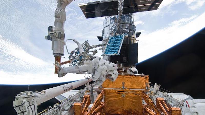 Michael Good (on the end of the shuttle's Remote Manipulator System) works to refurbish and upgrade NASA's Hubble Space Telescope during Servicing Mission 4. CREDIT: NASA