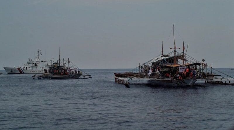 A Philippine Coast Guard ship is seen in the background as boats belonging to a civilian convoy sail toward Scarborough Shoal in the South China Sea, May 15, 2024. [Jojo Riñoza/BenarNews]