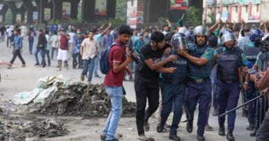 Policemen escort a colleague to safety after he was struck by a brick during a clash between pro-and anti-quota protesters, Dhaka, July 15, 2024. [Minhaz Uddin/BenarNews]
