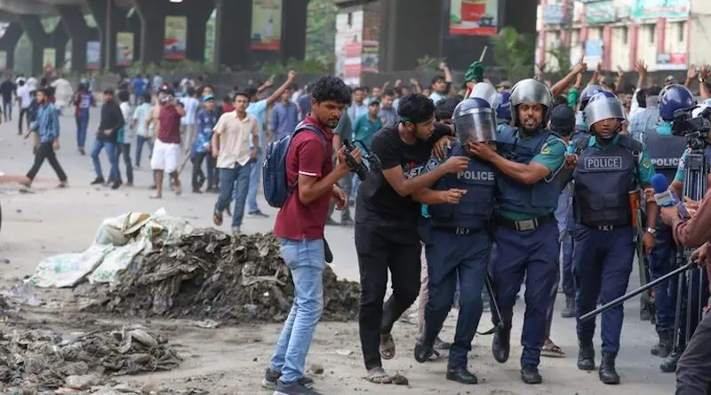 Policemen escort a colleague to safety after he was struck by a brick during a clash between pro-and anti-quota protesters, Dhaka, July 15, 2024. [Minhaz Uddin/BenarNews]