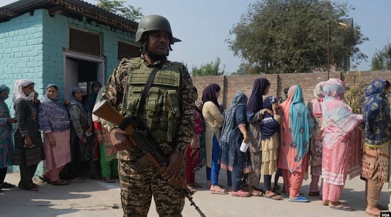 An Indian soldier stands guard as Kashmiris queue up at a polling station to cast their vote during the second phase of assembly elections, on the outskirts of Srinagar, Indian-administered Kashmir, Sept. 25, 2024. Photo Credit: Wasim Nabi for VOA