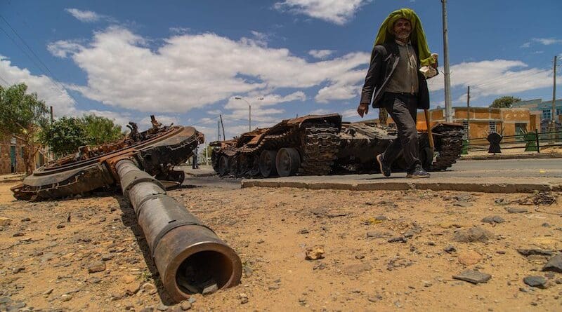 File photo of a man passing by a destroyed tank on the main street of Edaga Hamus, in the Tigray region, in Ethiopia. Photo Credit: Yan Boechat/VOA, Wikipedia Commons
