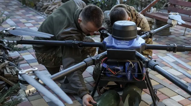 Ukrainian servicemen attach munitions to a modified drone. Photo Credit: RFE/RL