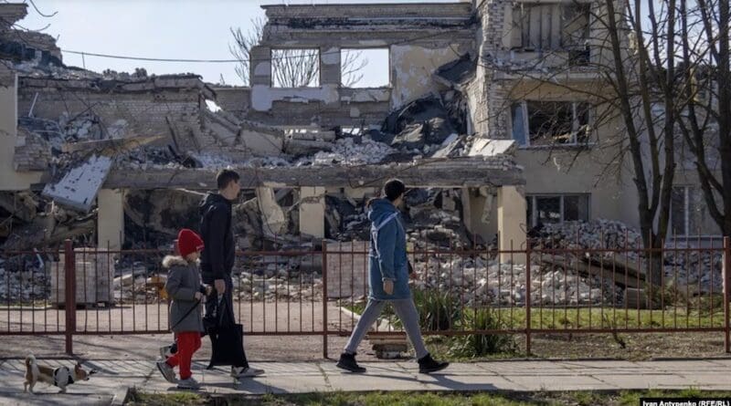 People walk in front of bombed buildings in Ukraine's Kherson. Photo Credit: RFE/RL