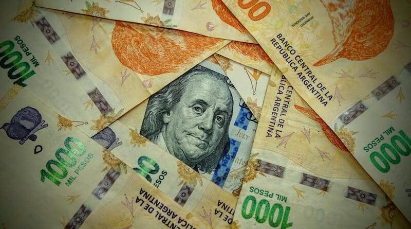 Detail of a 100 US dollar banknote among 1,000 Argentine peso notes. Photo Credit: Gaby Lopez, Pexels