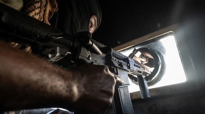 A Haitian police officer keeps watch while patrolling the streets of Port-au-Prince in an armoured vehcile. Photo Credit: © UNOCHA/Giles Clarke