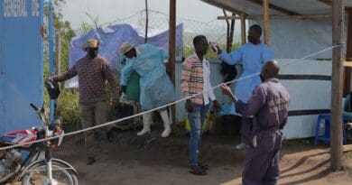A health worker screens a man at the entrance of a hospital in Ituri, DR Congo. Photo Credit: WHO/Joël Lumbala