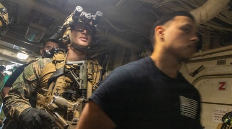 A U.S. Marine, with Maritime Raid Force, Littoral Combat Force-24, escorts a simulated detainee during a Maritime Interdiction Operation Full Mission Profile rehearsal aboard San Antonio-class amphibious transport dock USS San Antonio (LPD 17) off the coast of Venezuela, July 17, 2026. Photo Credit: Daniel Garcia, Marines, DVID